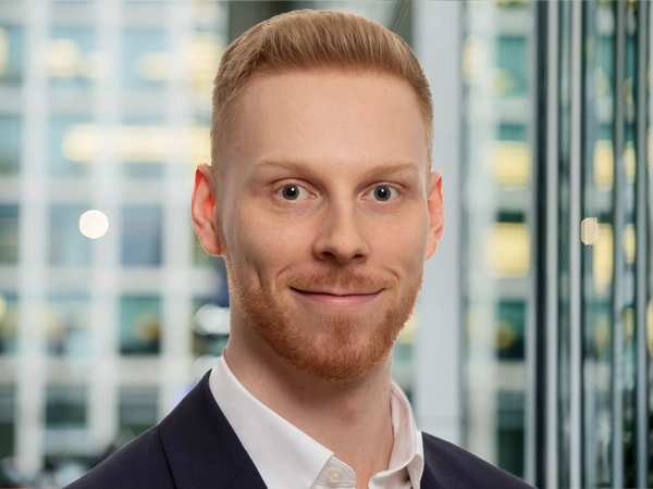 Portrait of Matt Lowe, Principal Consultant, with city landscape featuring building with lots of windows in the background.