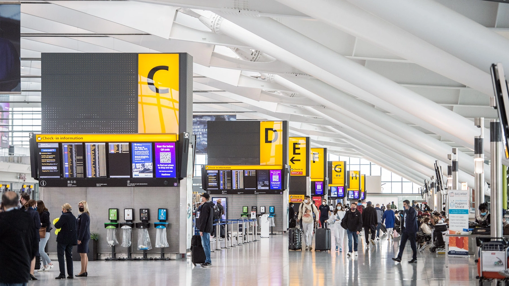 Airport with people walking through and boards showing flights.
