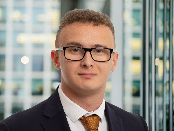 Portrait of Daniel Foreman, Associate, standing in window based office building smiling.