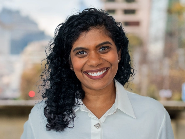 Portrait of Sonia Gomez, Associate Director, Marketing and Communications, Asia, Standing outside featuring an urban cityscape with tall buildings and a mix of architectural styles. The scene includes some trees with autumn foliage, adding a touch of color. 