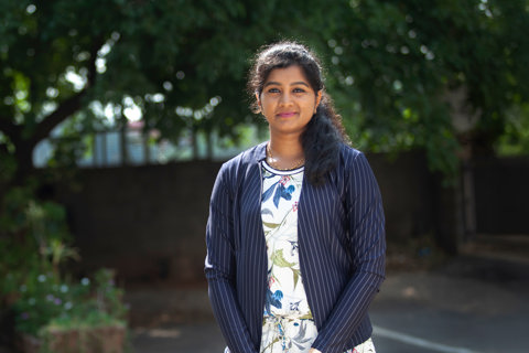 Portrait of Ashwini Dharmarajan, Senior Project Manager, Toronto, outside in front of trees.