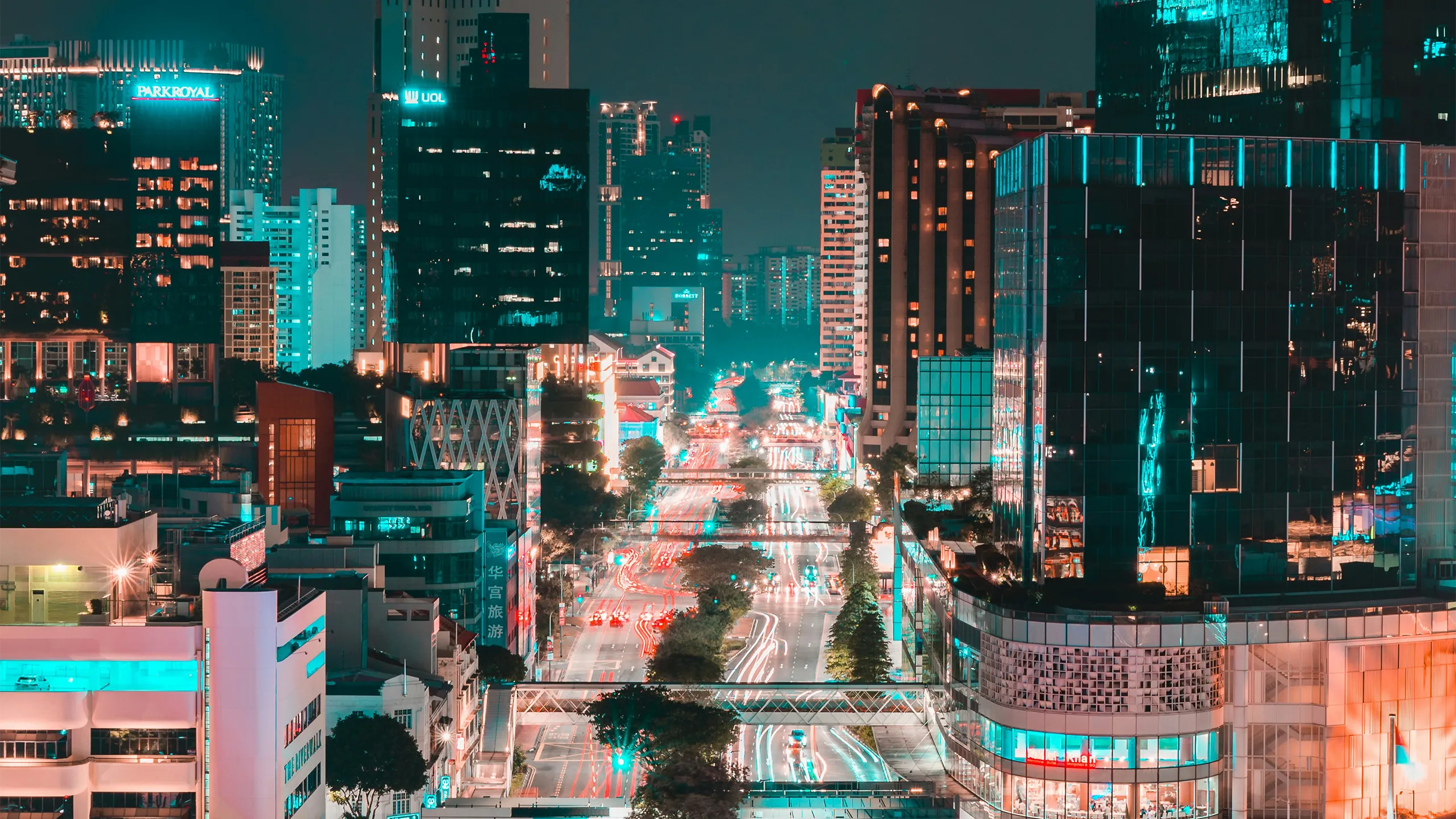 Singapore at night with glass skyscraper buildings and brightly lit roads with traffic