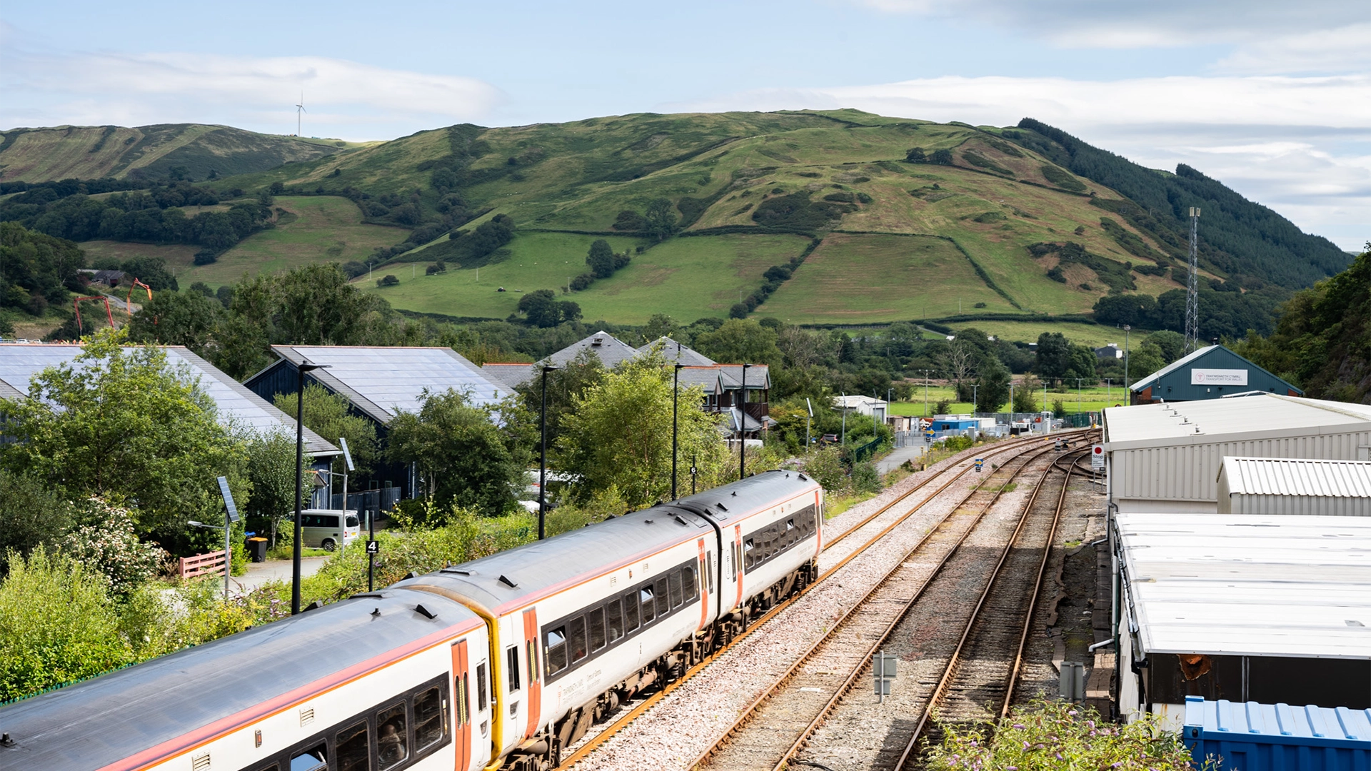 Train in a rural area, with green hill in the background