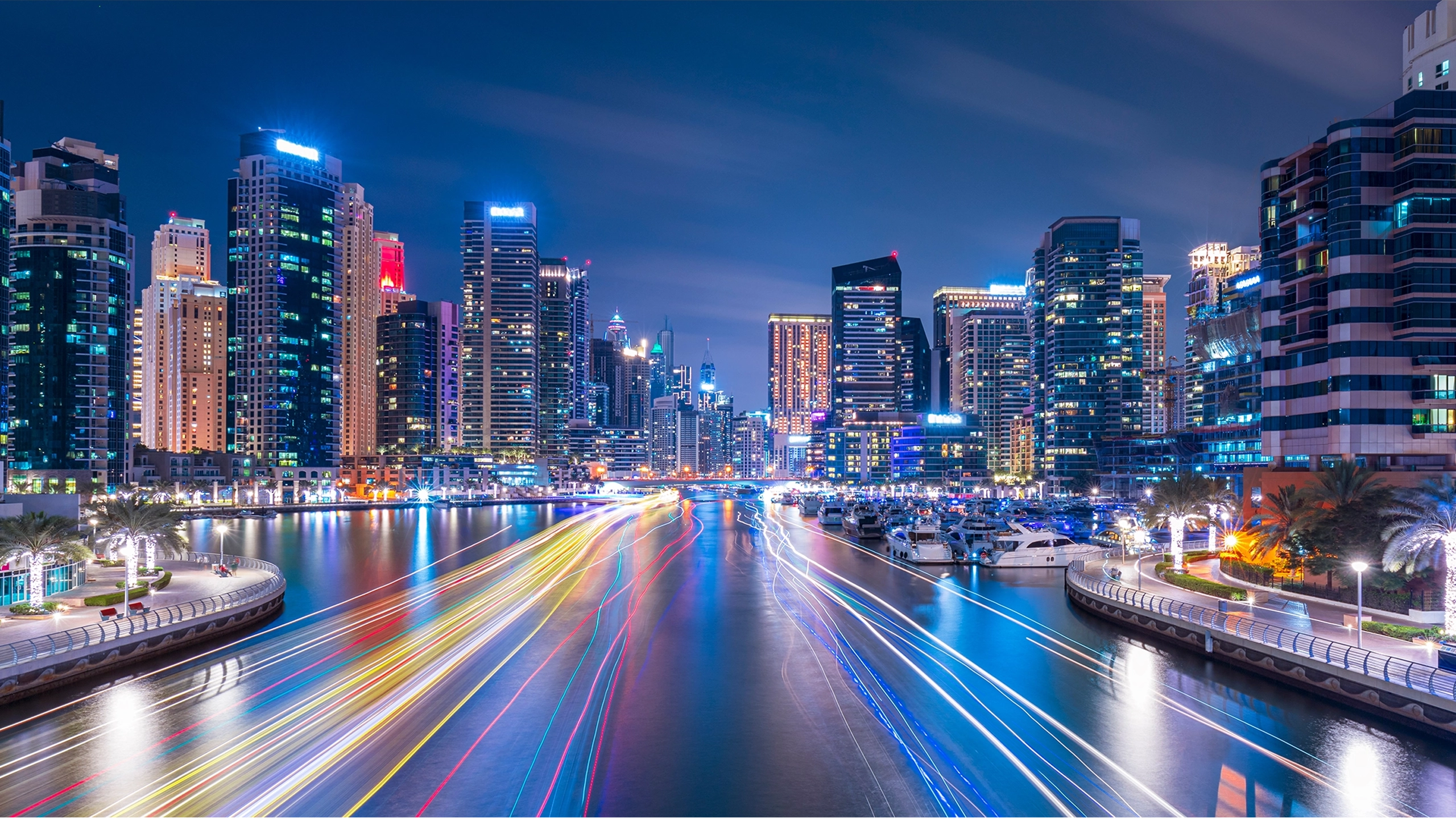 Skyscrapers at night alongside digitally imposed lines of colour on the water