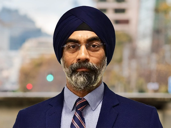 Portrait of Gurjot Bhatia, Managing director, South Asia, Standing outside featuring an urban cityscape with tall buildings and a mix of architectural styles. The scene includes some trees with autumn foliage, adding a touch of color. 