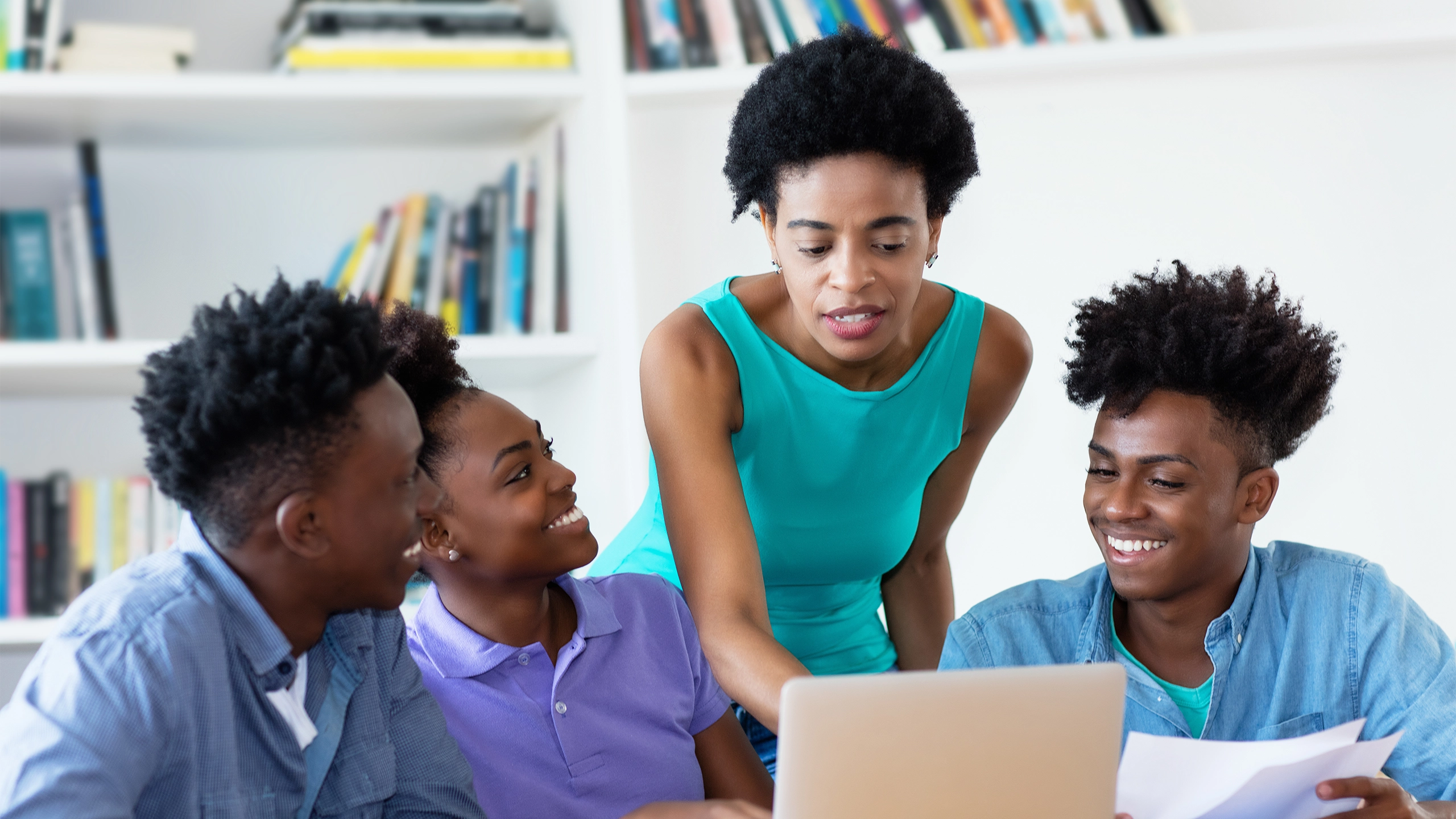 Group of four gathered around laptop smiling