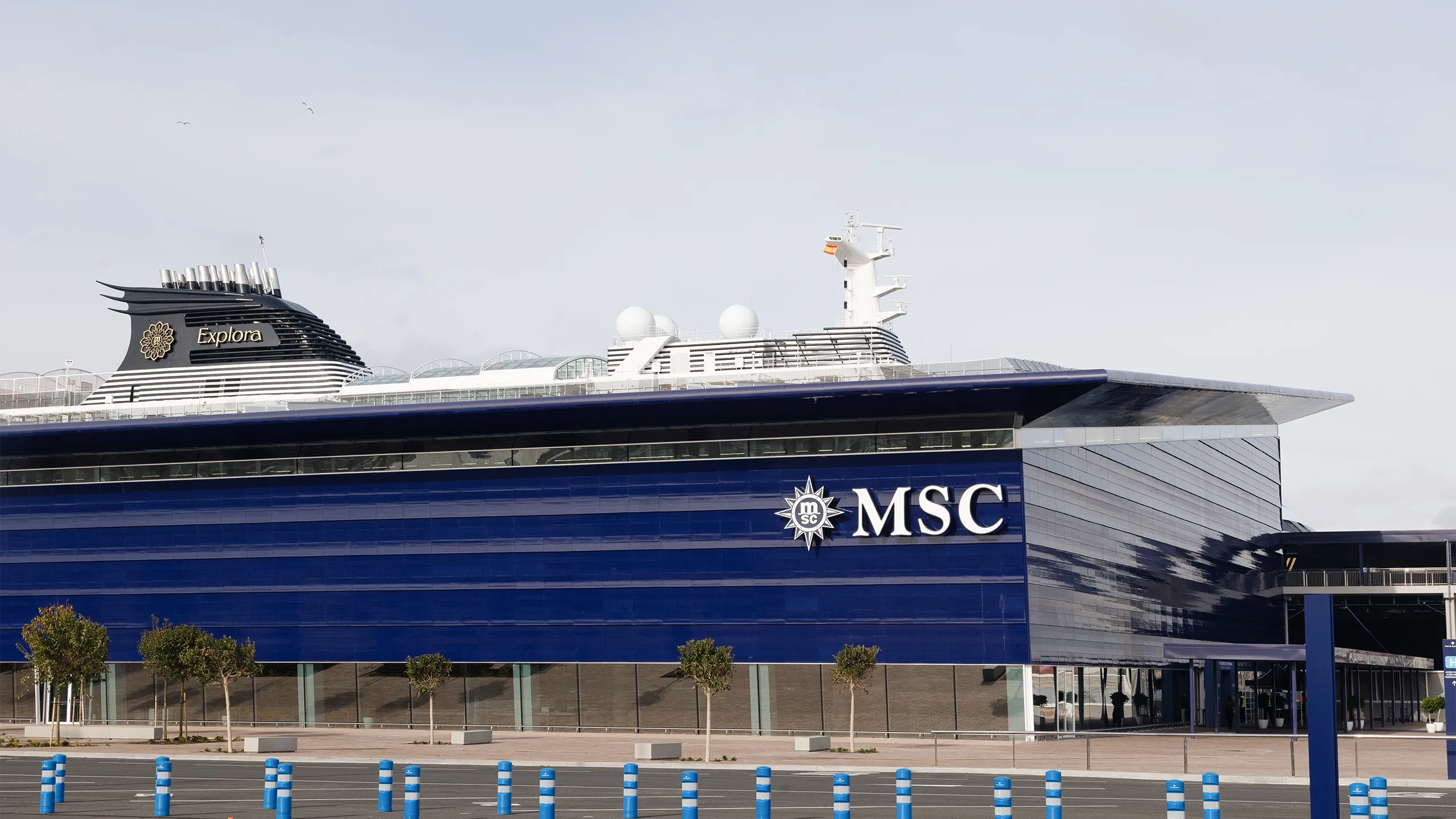 Modern blue MSC building with a large overhanging roof and glass fronted entrance, set in an open plaza
