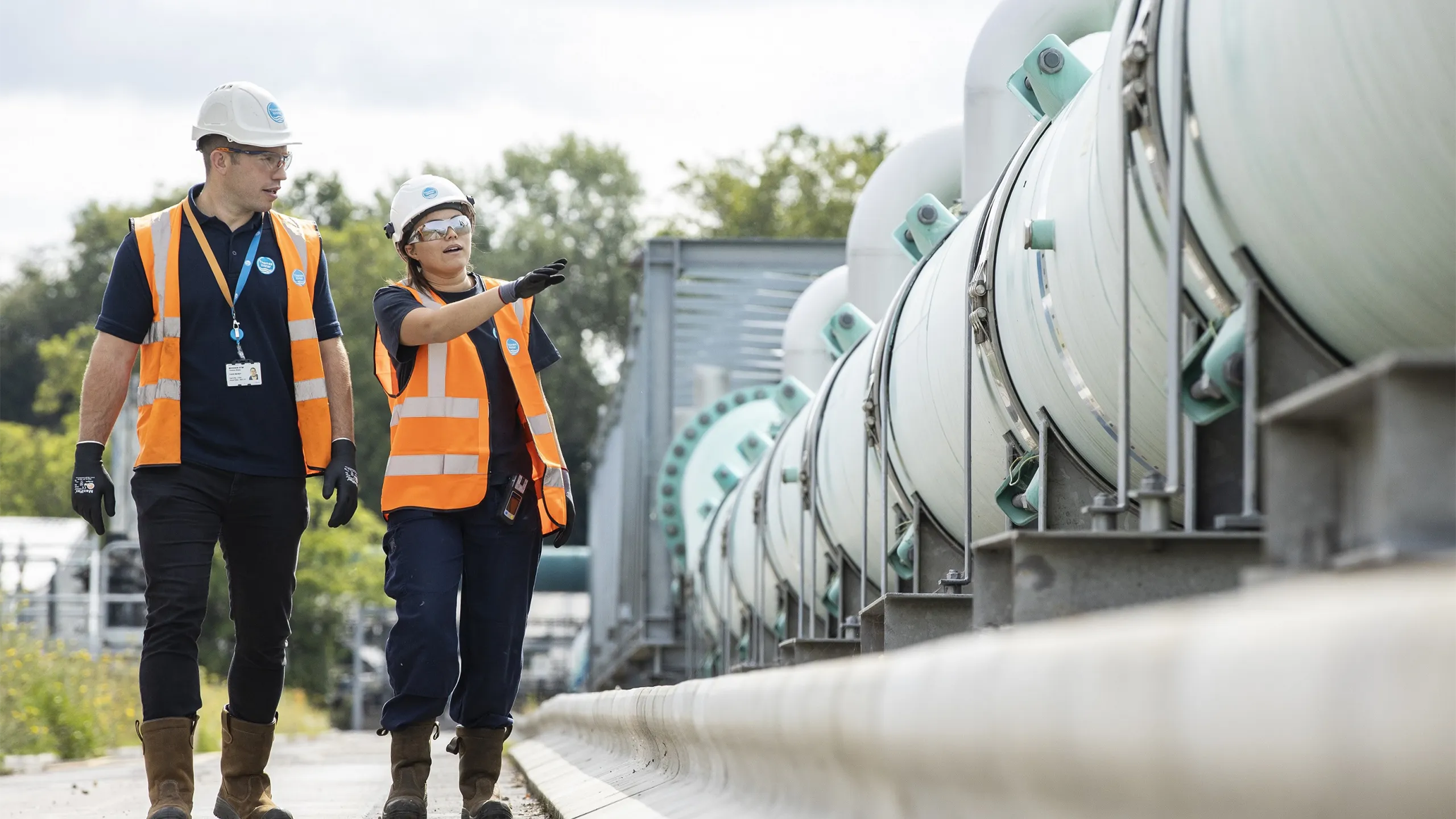 Smiling contractors walking along rows of concrete mixer trucks and planning working day at construction site