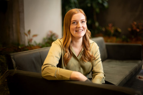 Portrait of Katie Demack, Senior Project Manager, Australia, close up wearing green shirt with greenery in background.