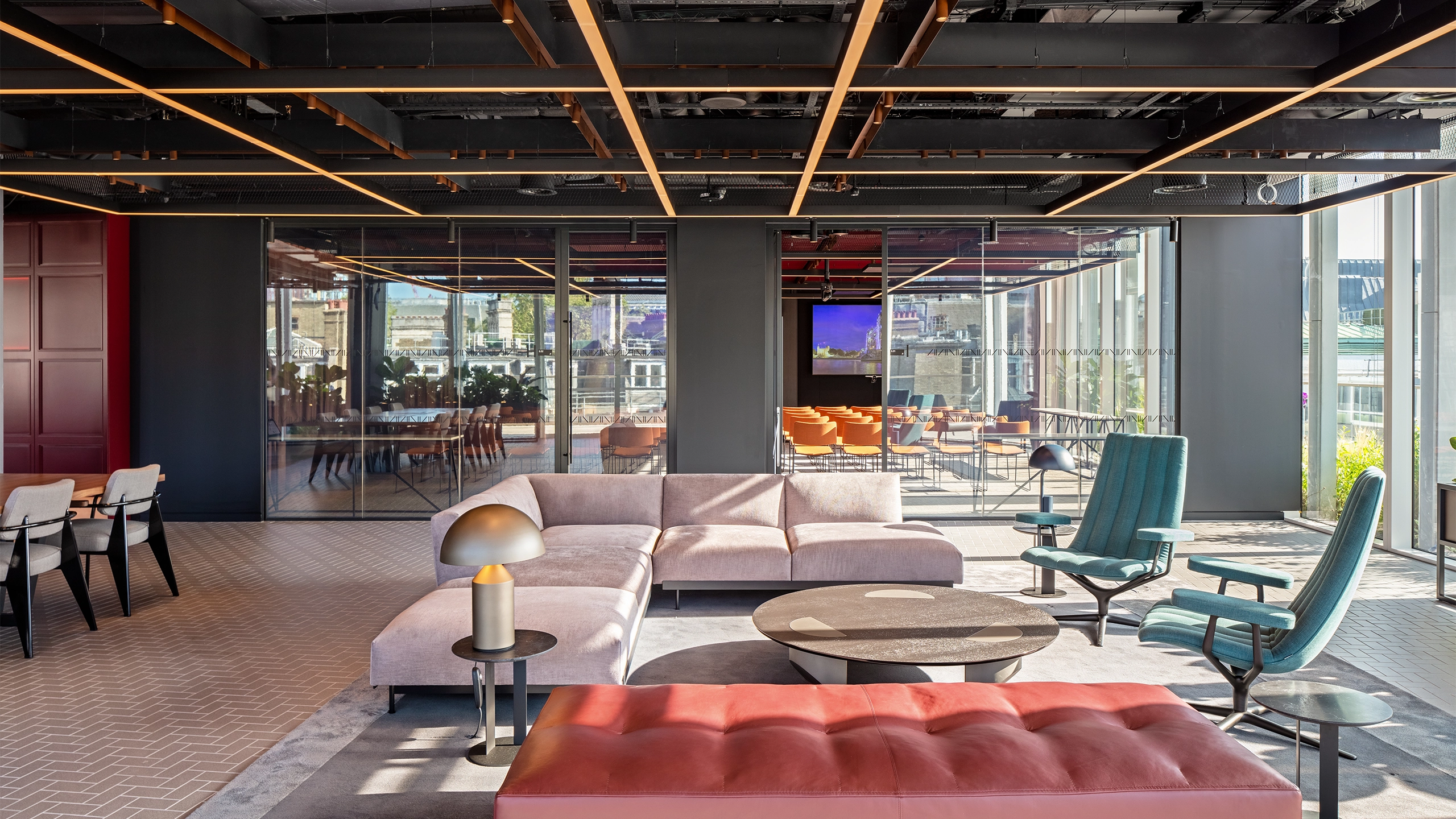 Modern, light-filled office interior with sofas in the foreground and a glass meeting room in the background