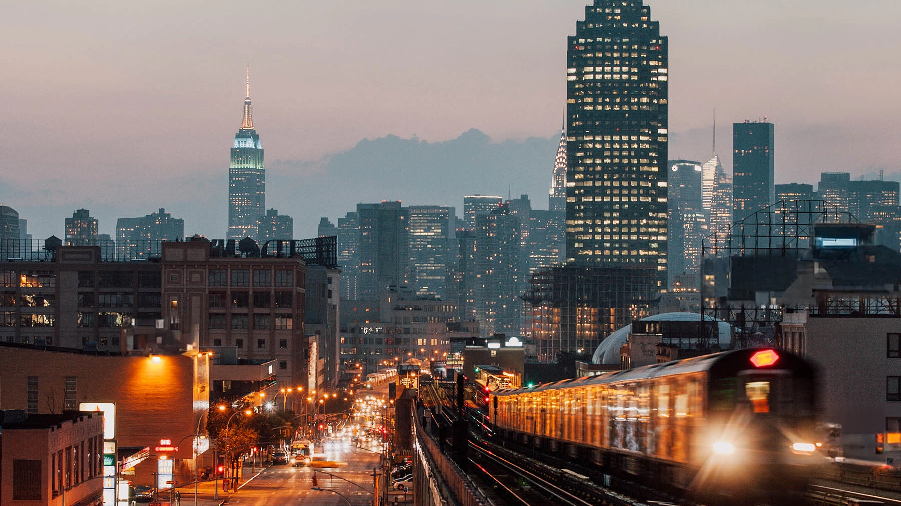 New York skyline at night with trains, skyscrapers and cars