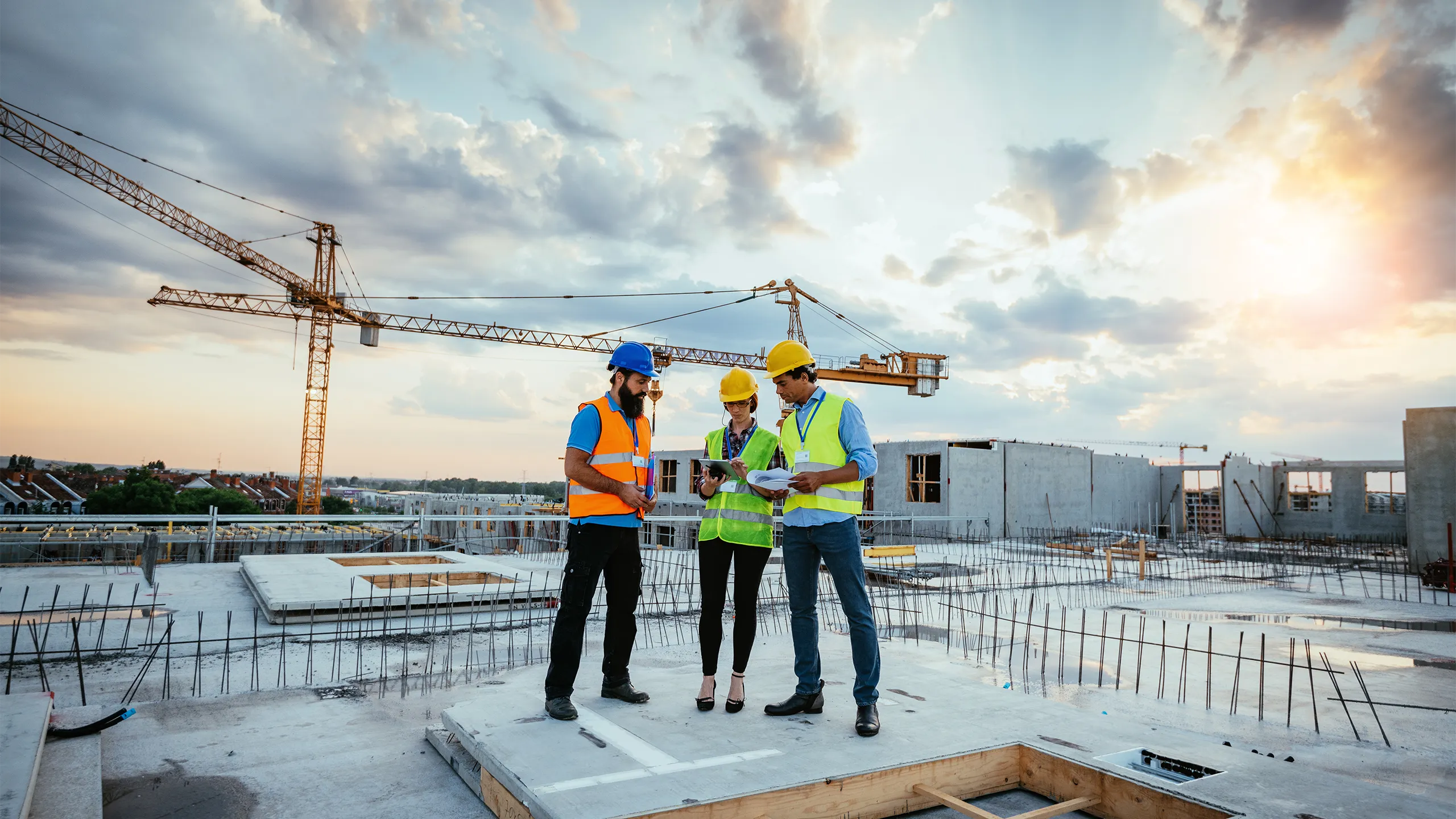 Employees working on construction site, wearing protective equipment and discussing next construction phase