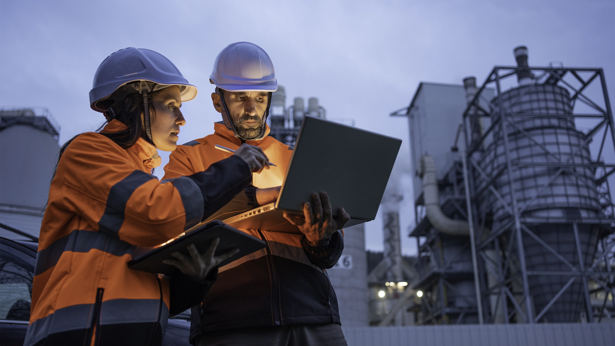 Male and female construction workers wearing high vis and looking at a laptop