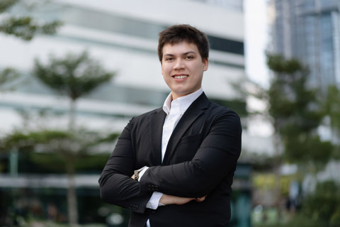 Vincent Tameeris, Assistant Consultant, Singapore, standing outside an office with his arms folded, smiling