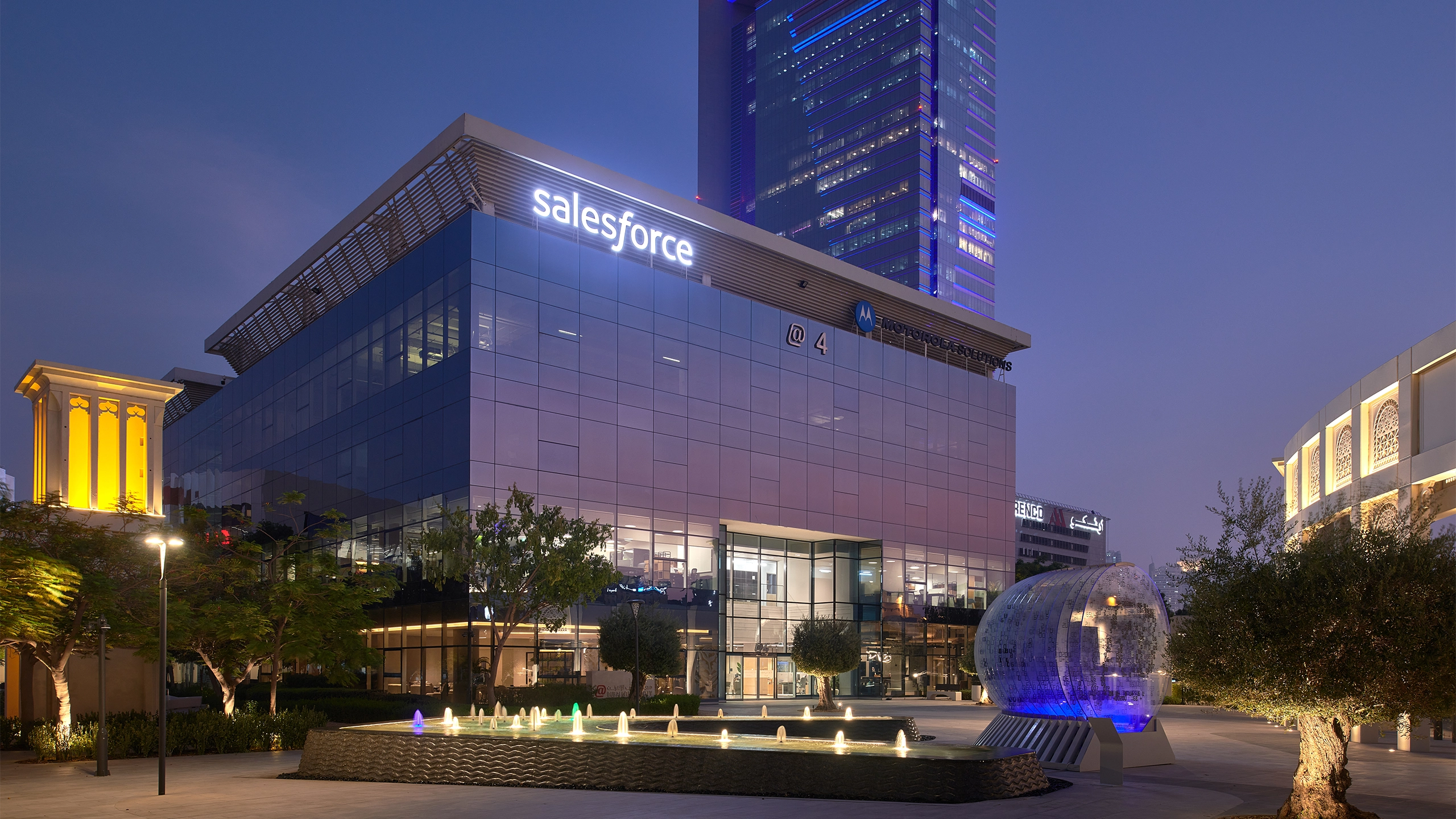 Image of Dubai Salesforce office at night, glass windows that reflects the purple ambiance of the night sky.