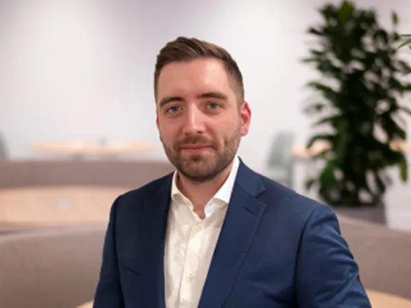 Portrait of Paul Barry, Data Centre Sector Lead, NAM, standing in plant based office in blue blazer.