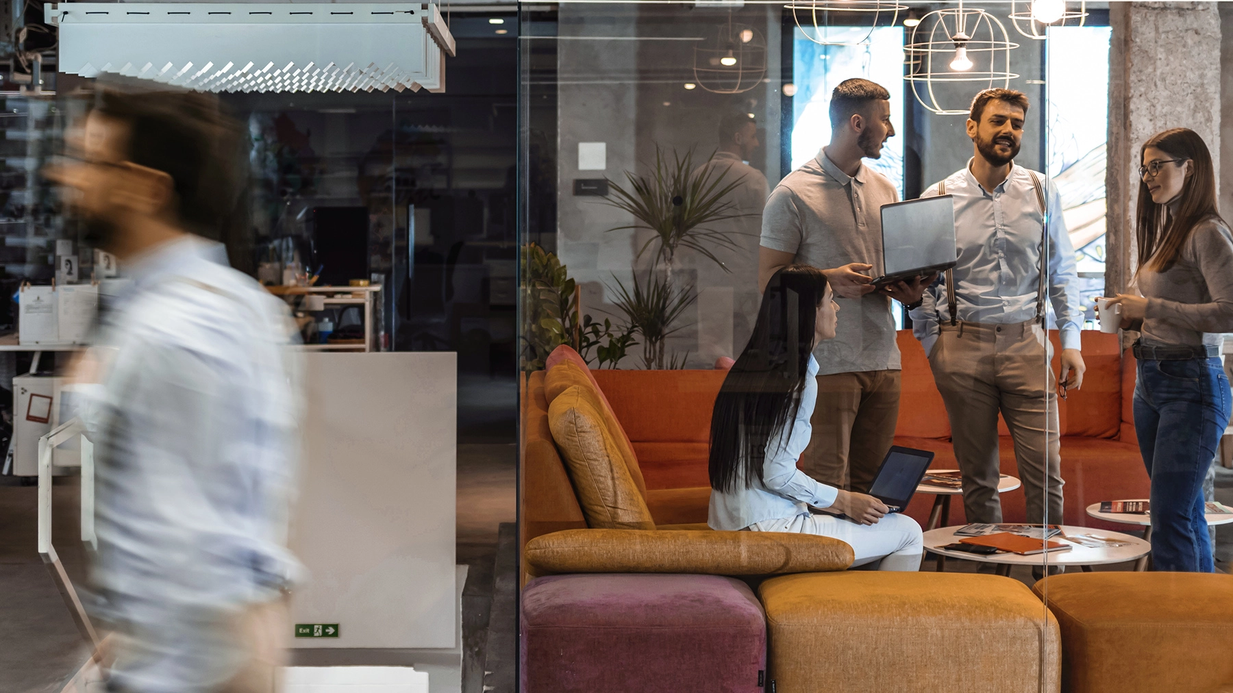 Colleagues standing around in a colourful based office, engaged in a conversation.