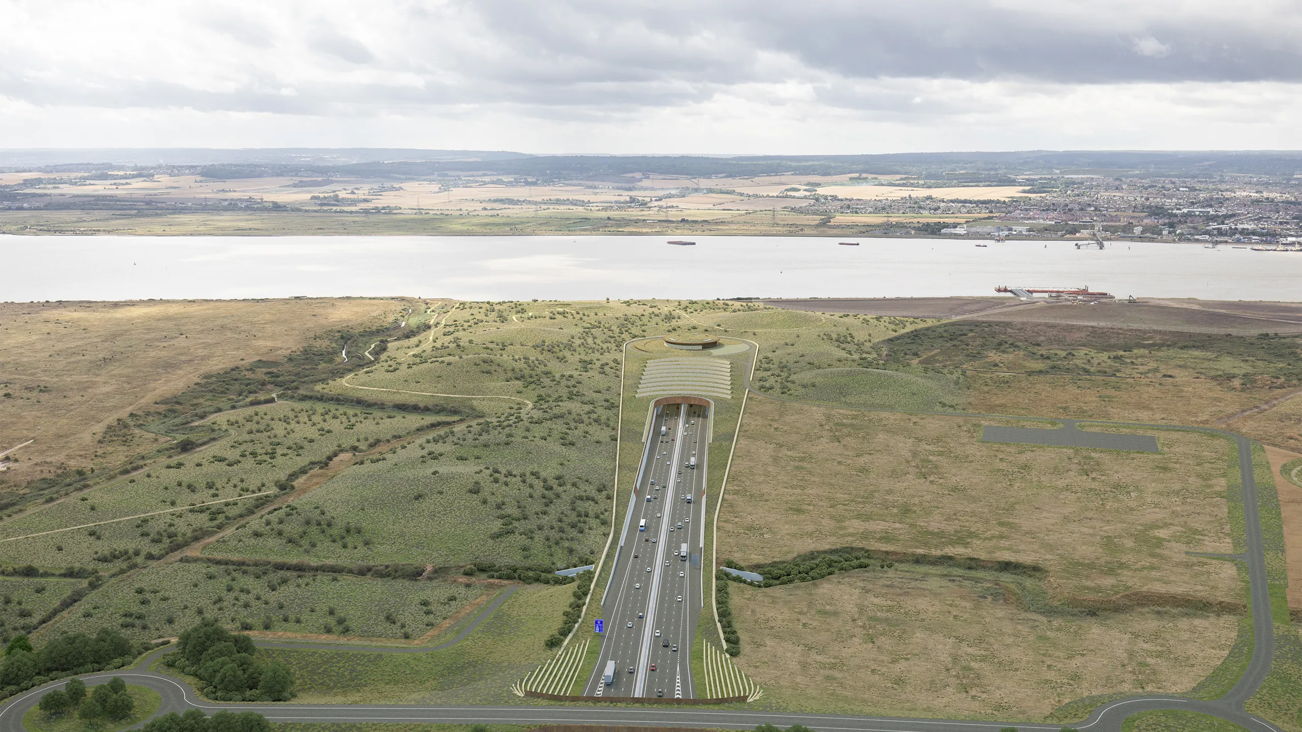 Portrait of highway surrounded by green fields and river.