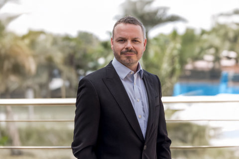 Portrait of Ryan Shalabi, Middle East Expert Lead, outside in front of blurry green scenery and trees.