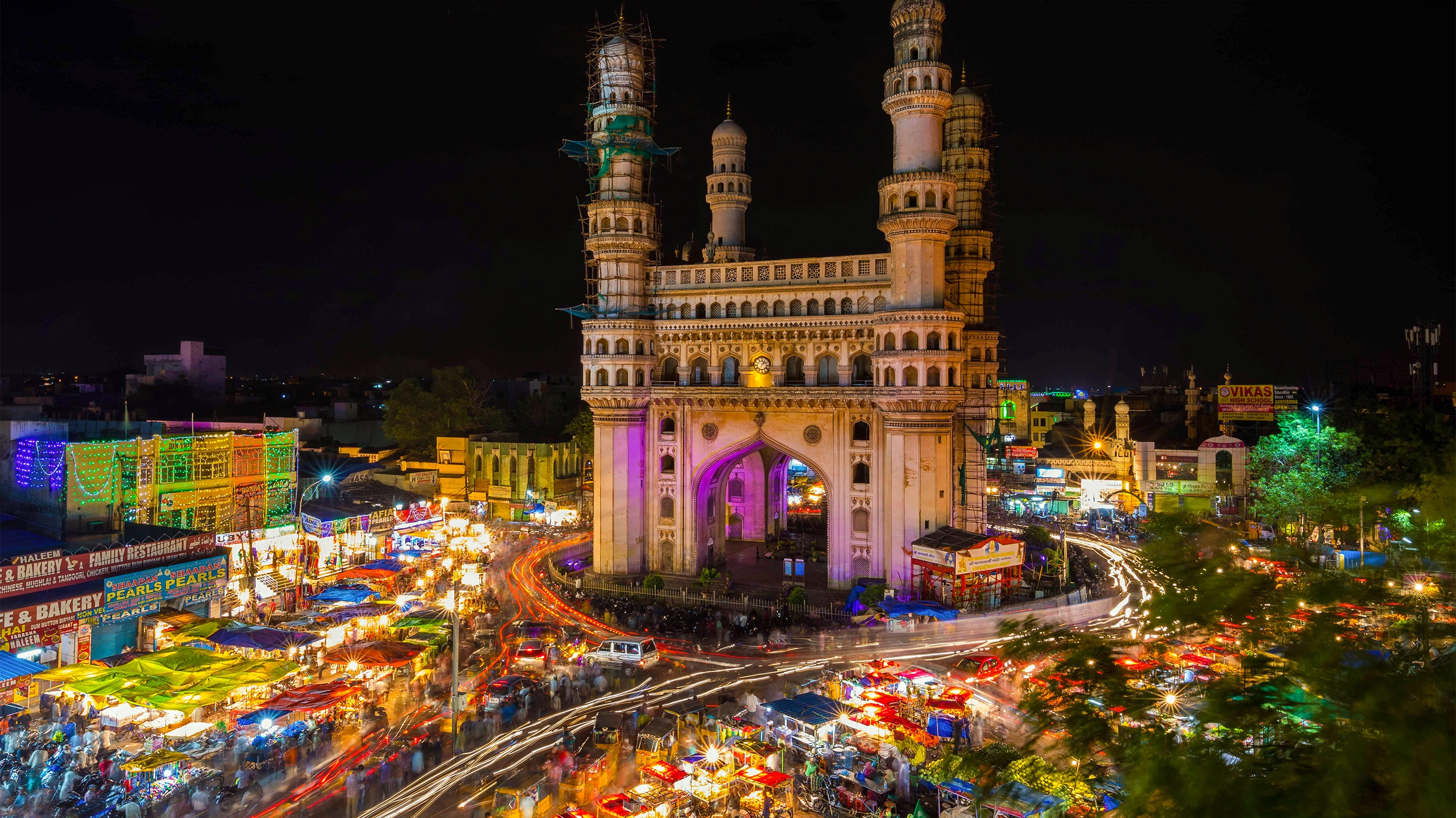 Long-exposure photo of traffic moving around the Charminar monument at night in the city of Hyderabad